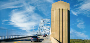 Cars driving over a bridge with a blue sky with a few clouds