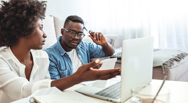 Young couple looking at a computer laptop screen and discussing